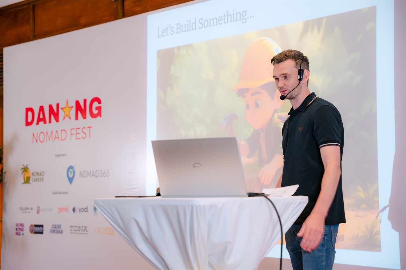 Sean McCloskey on stage beside a 'Let's Build Something' slide, presenting at Nomad Fest in Da Nang